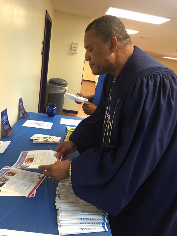 Rev. Leroy Jones reads information on the display table about autism.